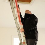 Home inspector checking the attic of a house during a pre-delivery inspection.