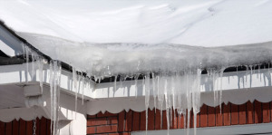 Icicles and ice dams on formed on the roof of a house.